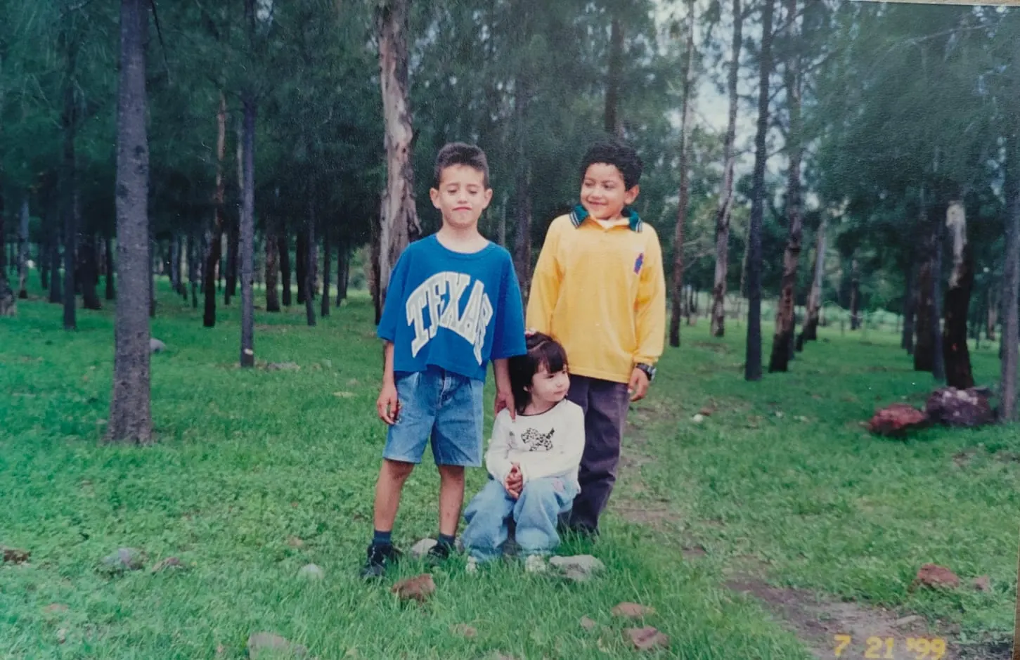 Tres niñas y niños posando en un bosque de pinos